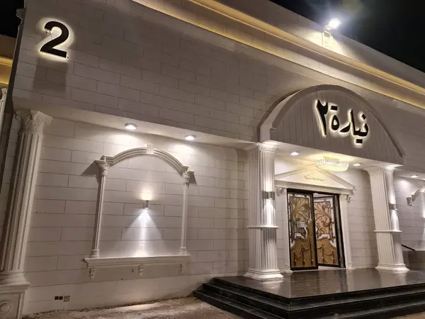 مدخل «نيارة ٢» بواجهة بيضاء وباب مزخرف وإضاءة ليلية