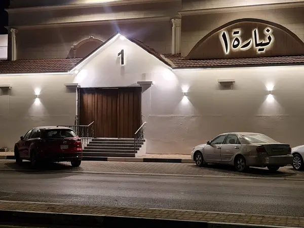 واجهة قاعة نيارة الأحساء ليلًا ومدخل «نيارة ١» والمواقف أمامها